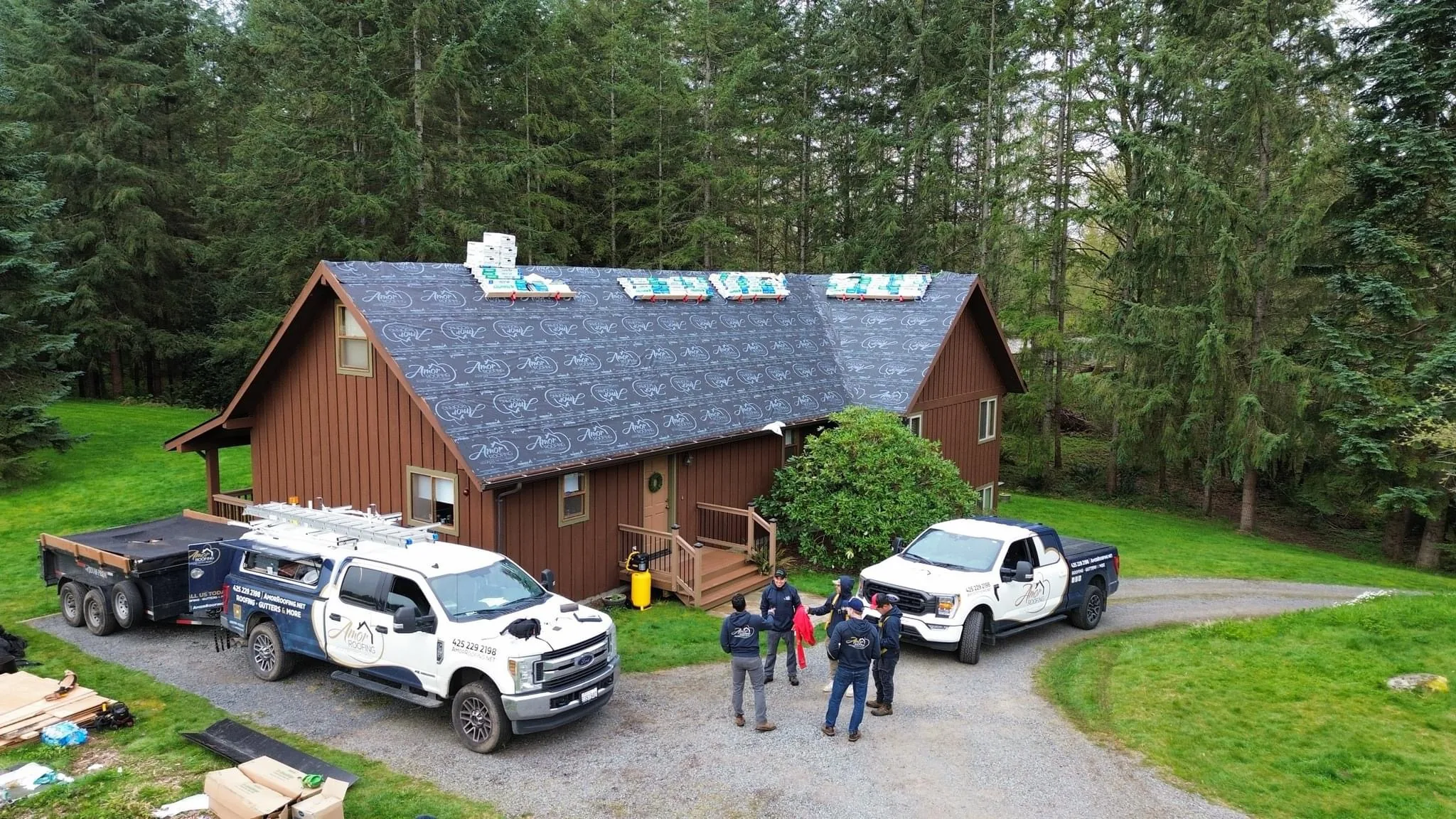 The Amor Roofing crew with branded trucks on a completed install